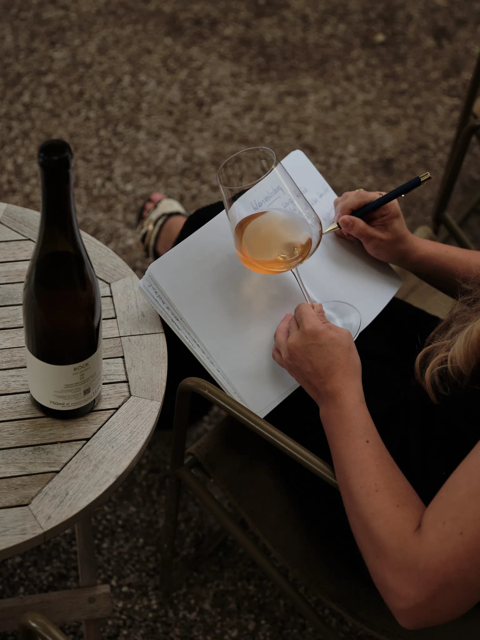 Rosa notiert Verkostungsnotizen neben einem Glas Wein